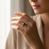 Bague or jaune 9 carats et perle de culture noire de Tahiti portée à la main.
