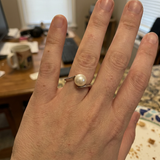 Bague zigzag en or blanc 9 carats ornée d'une perle de culture blanche, portée à l'annulaire.
