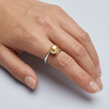 Bague zigzag en or blanc 9 carats ornée d'une perle de culture dorée, portée à l'index.