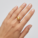 Bague zigzag en or jaune 9 carats ornée d'une perle de culture dorée, portée à l'annulaire.