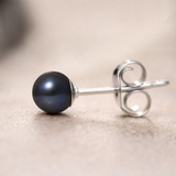 Boucle d'oreille argent 925 avec perle de culture noire de Tahiti, vue de profil sur fond beige.