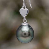 Boucles d'oreilles argent 925 en forme de cœur avec perle noire de Tahiti en gros plan.