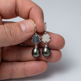 Boucles d'oreilles argent 925 trèfle avec perles noires en goutte, tenues dans une main.
