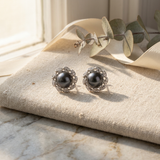 Boucles d'oreilles argent 925 ornées d'une perle noire de Tahiti, entourée de motifs feuilles pavés.