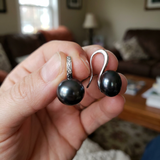 Boucles d'oreilles argent 925 à perles noires de Tahiti, tenues en main.