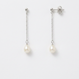 Boucles d'oreilles pendantes en or blanc 9 carats avec perles blanches ovales sur chaîne fine.