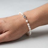 Bracelet en argent 925 et perles blanches 5/6 mm avec fermoir boule, porté au poignet.