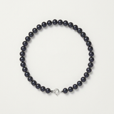 Bracelet en argent 925 et perles noires 5/6 mm avec fermoir boule, posé sur fond neutre.