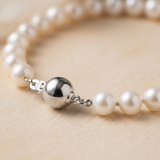 Gros plan sur le fermoir boule en argent 925 d'un bracelet de perles blanches.