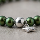 Gros plan bracelet perles d'eau douce vertes argent 925 avec charm étoile et perle centrale argentée.