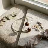 Bracelet jonc ouvert en argent 925 avec deux perles chocolat aux extrémités.