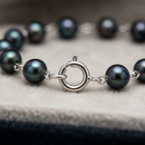 Gros plan sur le fermoir anneau en or blanc 9 carats du bracelet à perles noires.