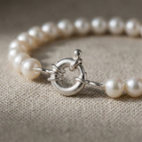 Bracelet perles blanches 6/7 mm argent 925 avec fermoir anneau en gros plan sur tissu beige.