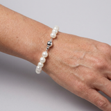 Bracelet perles blanches 8/9 mm et argent 925 avec fermoir boule, porté au poignet.