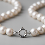 Gros plan sur le fermoir anneau en argent 925 d'un bracelet de perles de culture blanches.