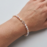 Bracelet en argent 925 orné de perles de culture multicolores roses et mauves, porté au poignet.