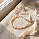 Bracelet en perles de culture roses et argent 925, présenté à plat sur un tissu beige.