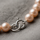 Gros plan sur le fermoir en argent 925 d'un bracelet de perles de culture roses.