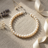 Bracelet en perles d'eau douce blanches avec fermoir en argent 925, posé à plat.