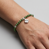 Bracelet perles d'eau douce vertes et argent 925 avec charm trèfle porté au poignet.