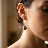 Boucles d'oreilles créoles or blanc 9 carats avec perle de Tahiti baroques portées à l'oreille.