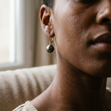 Boucles d'oreilles dormeuses or jaune et perle de Tahiti noire portées à l'oreille.