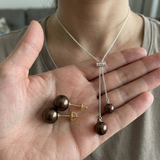 Collier lasso et boucles d'oreilles à perles chocolat présentés dans une paume.
