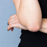 Bague jonc croisée en argent 925 avec oxyde de zirconium noir, portée à la main.
